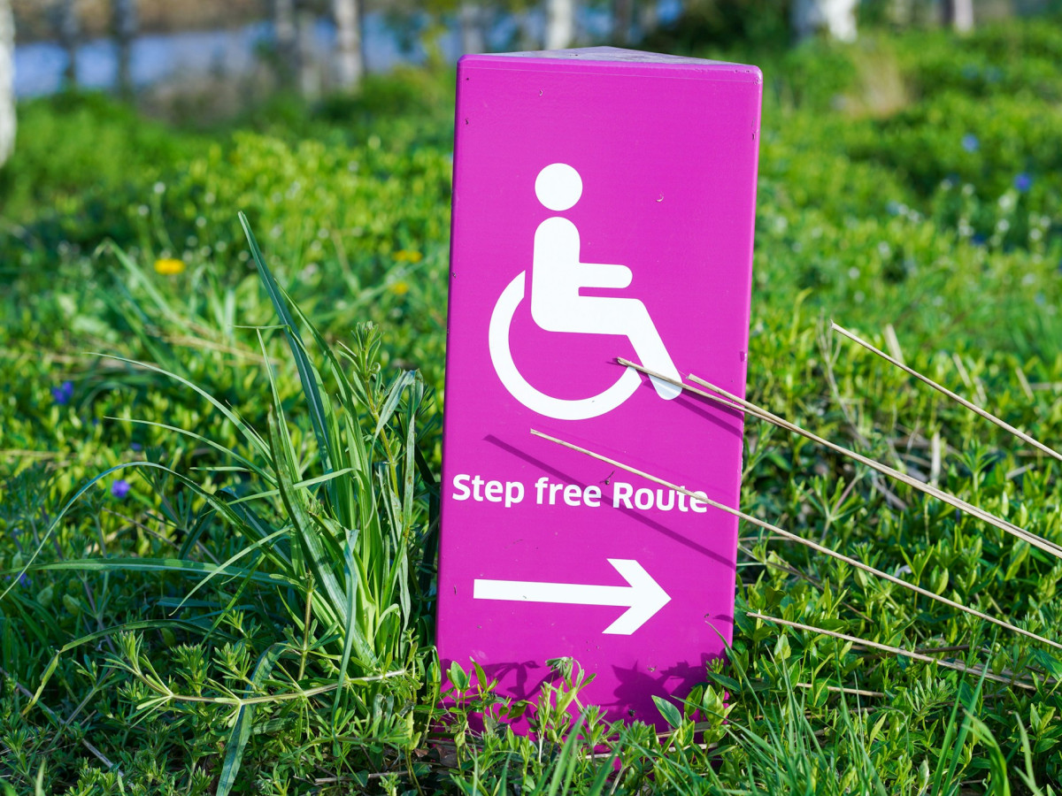 Rosafarbenes Schild mit der Aufschrift „Step free Route“ und einem Pfeil nach rechts – symbolisiert den Weg zu barrierefreien Webseiten.