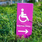 Rosafarbenes Schild mit der Aufschrift „Step free Route“ und einem Pfeil nach rechts – symbolisiert den Weg zu barrierefreien Webseiten.